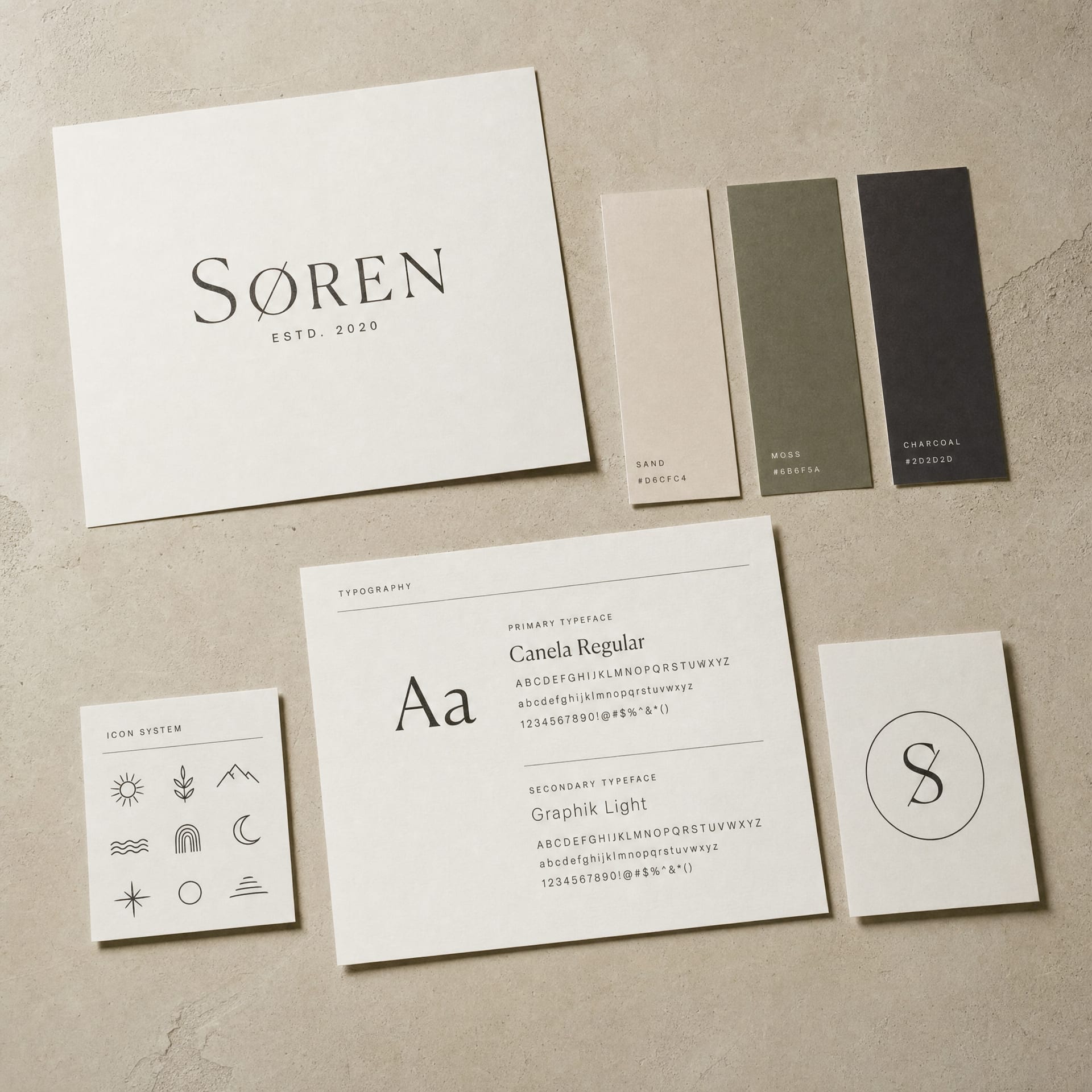 An overhead studio still life of a brand identity visual system: wordmark sheet, colour swatches, type specimen and monogram card.