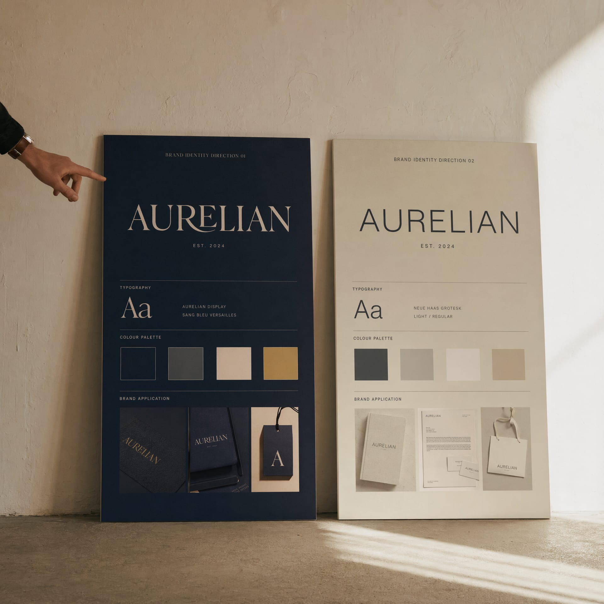 Two distinct identity direction boards leaning side by side against a plaster wall, a hand pointing at the left one.