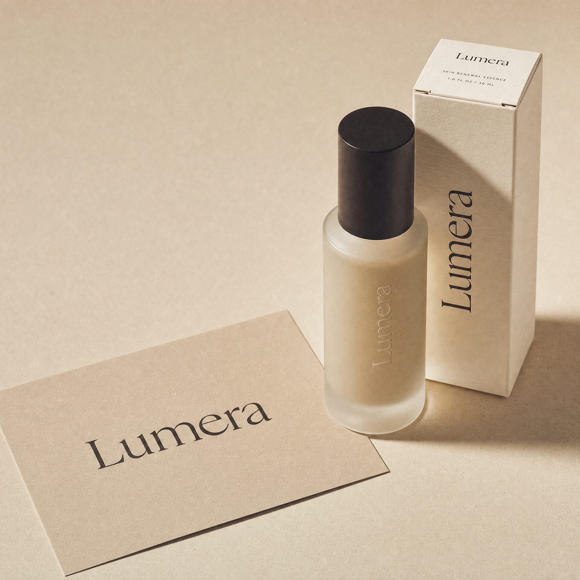 Sand-toned printed wordmark card for Lumera beside a frosted bottle and an ivory carton, all carrying the same mark.