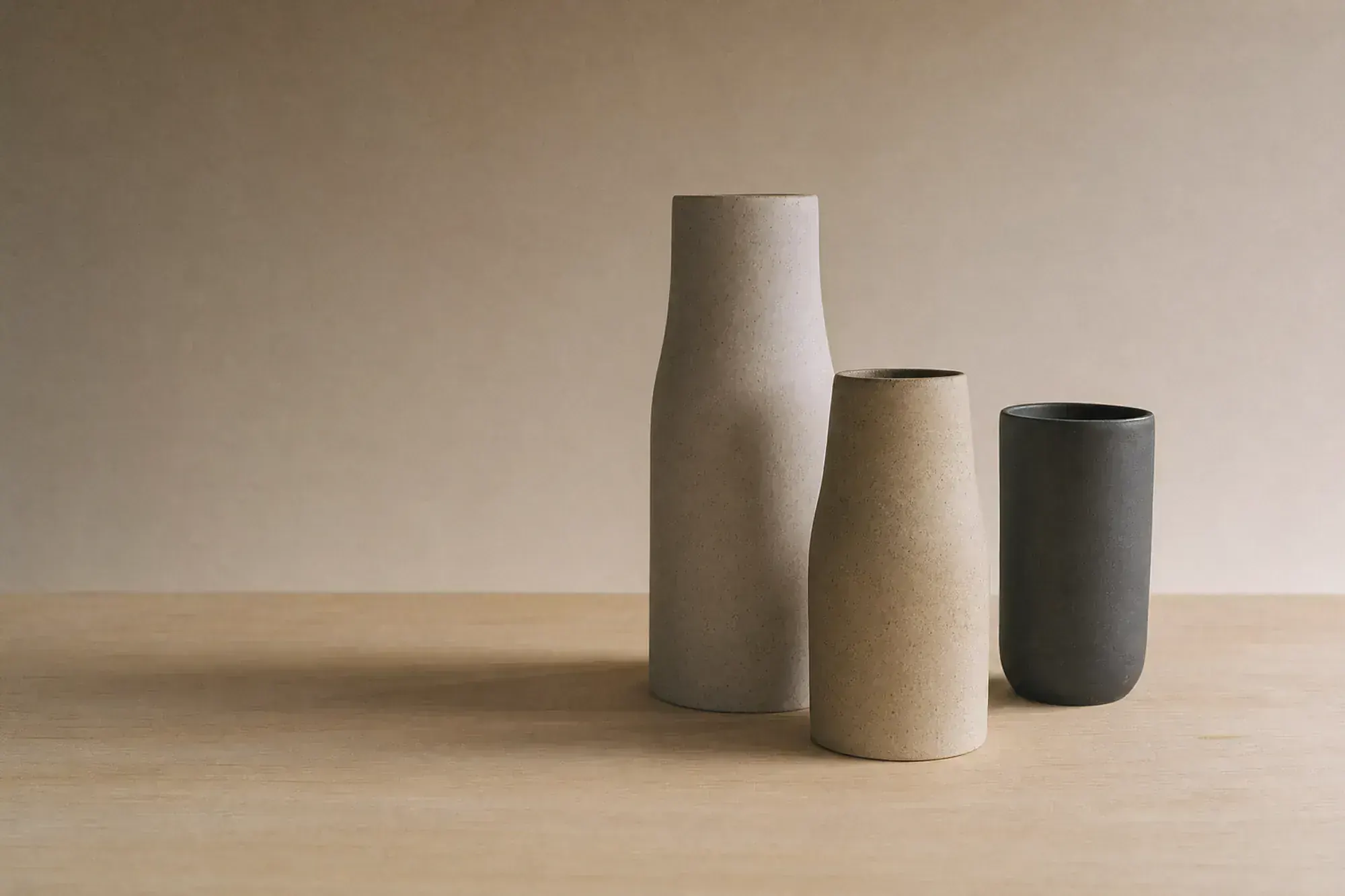 A matte navy ovoid resting on a cream plinth, half-revealed from behind a draped panel of cream linen.